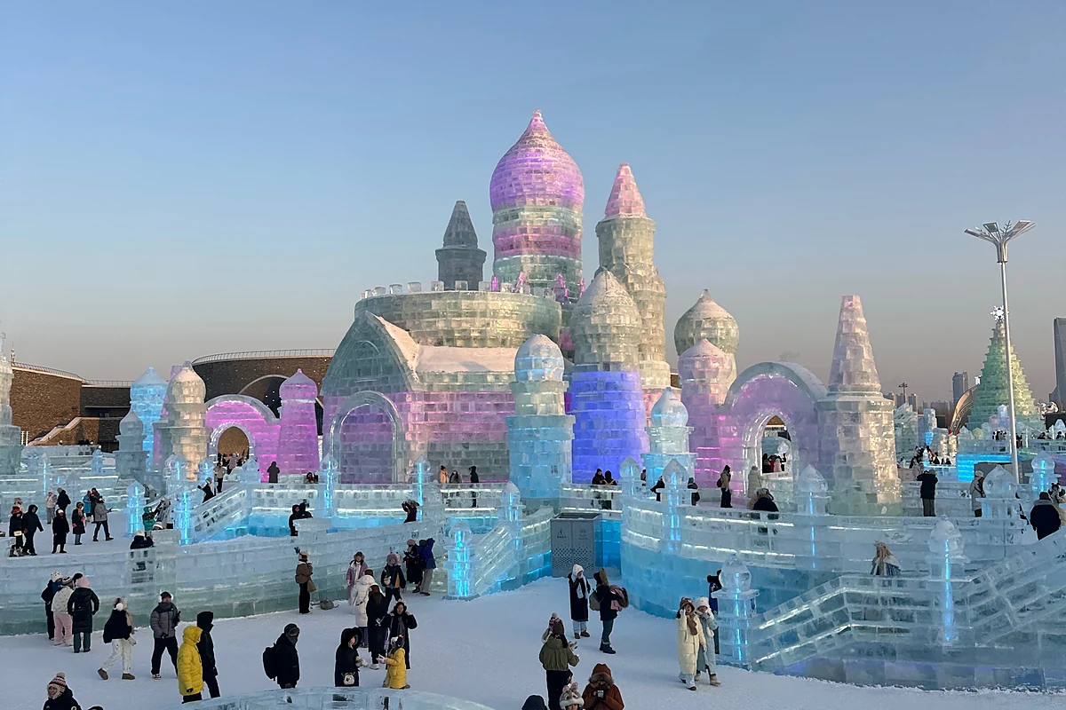 Ice replica of Saint Sophia Cathedral inside Harbin Ice and Snow World, pink dome and blue ice walls with visitors in front