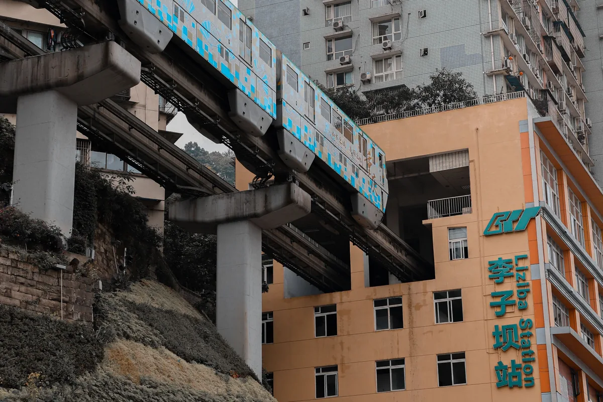 Chongqing Line 2 monorail train entering the Liziba Station building, with the station sign 李子坝站 on the facade