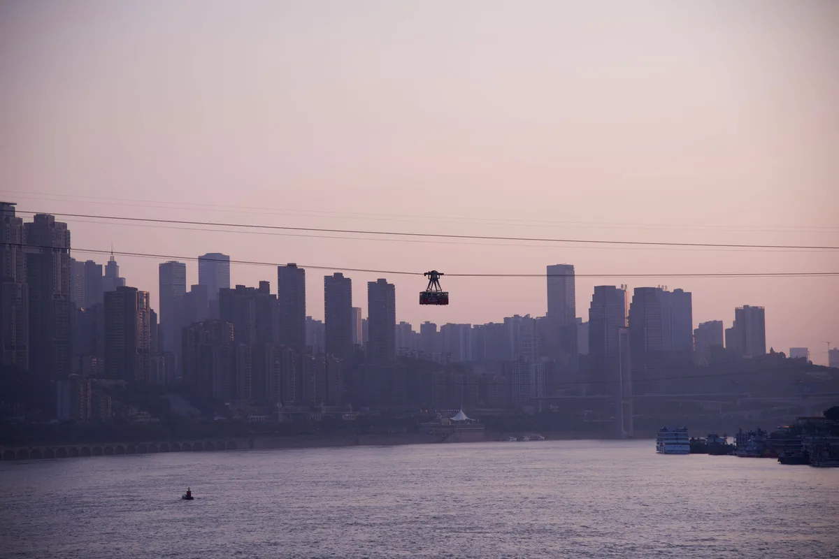 Yangtze River Cableway cabin crossing the river at dusk with the Chongqing skyline in silhouette