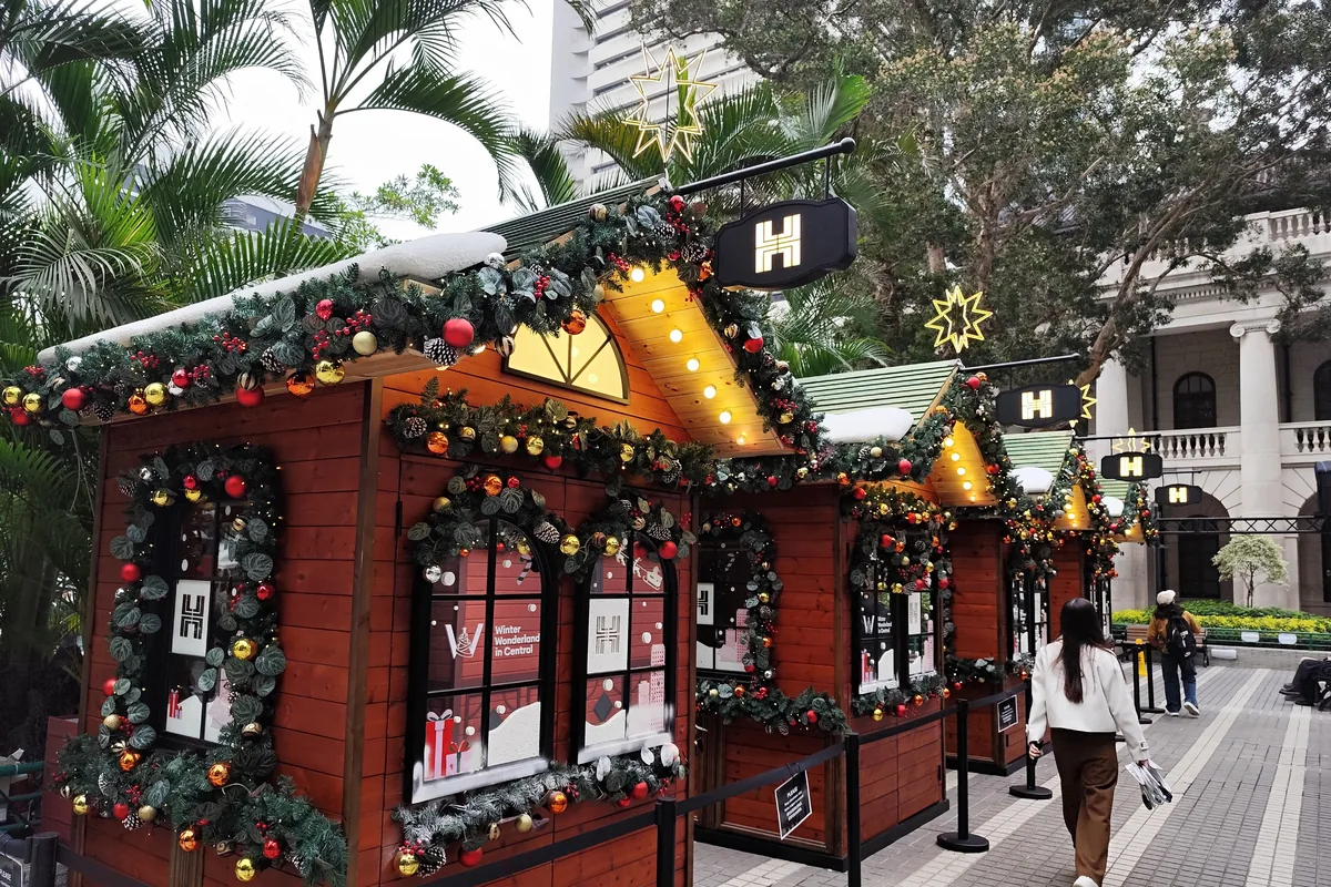 Wooden Christmas market chalets with wreaths and garlands under palm trees in Central, Hong Kong