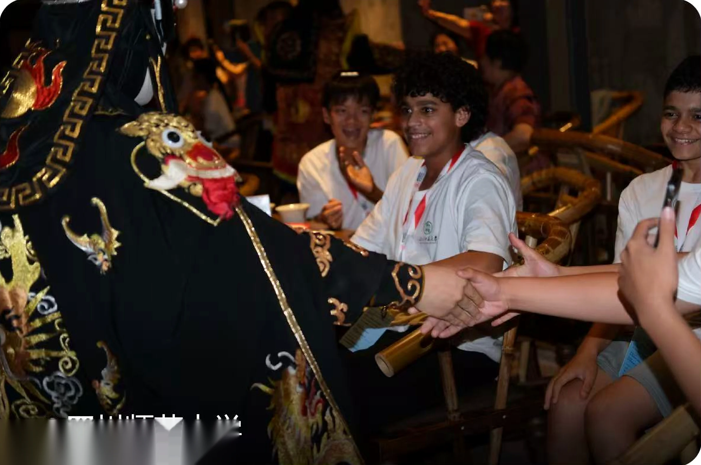 Sichuan opera face-changing performer in ornate costume shaking hands with an international study-tour student
