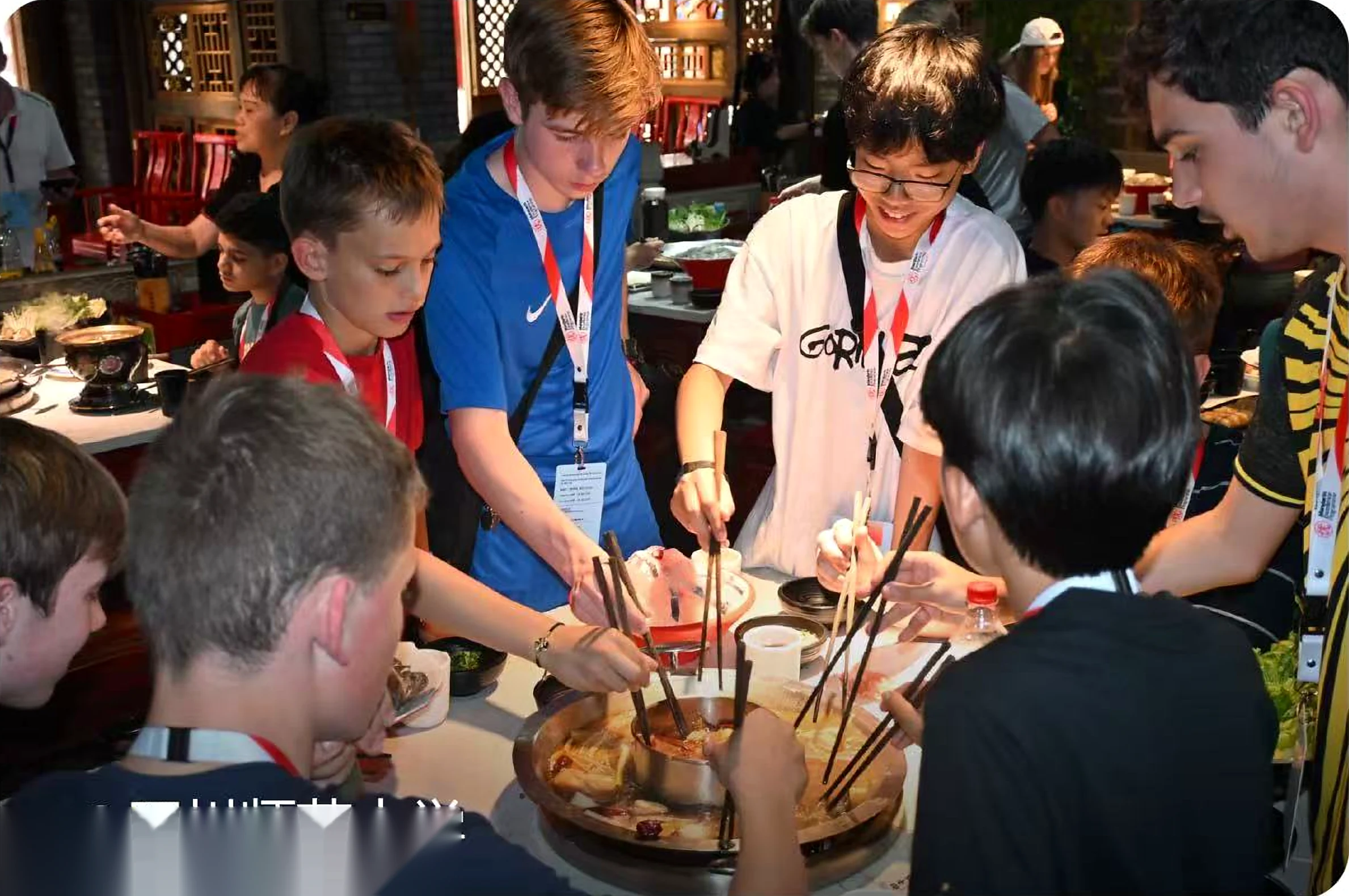 International study-tour students sharing Sichuan hotpot around a restaurant table