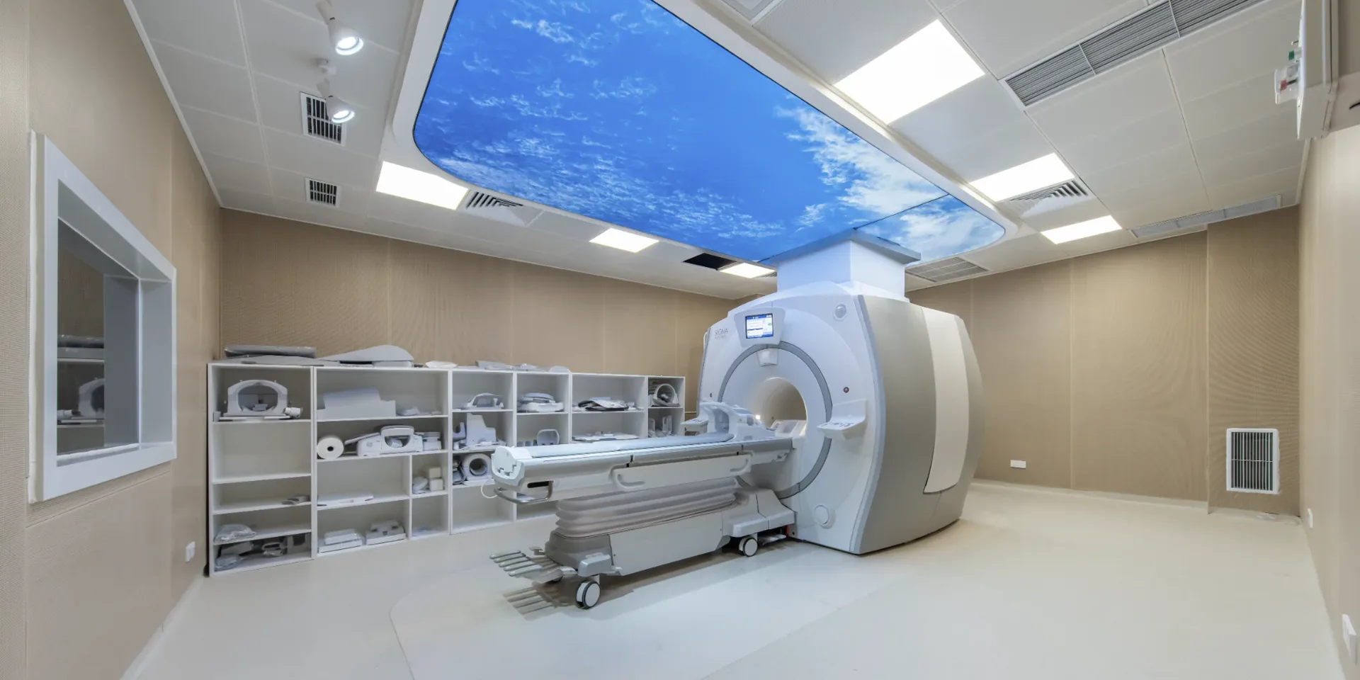Empty GE SIGNA MRI suite at the Shenzhen partner facility, with a sky-ceiling panel, patient table, and control-room window