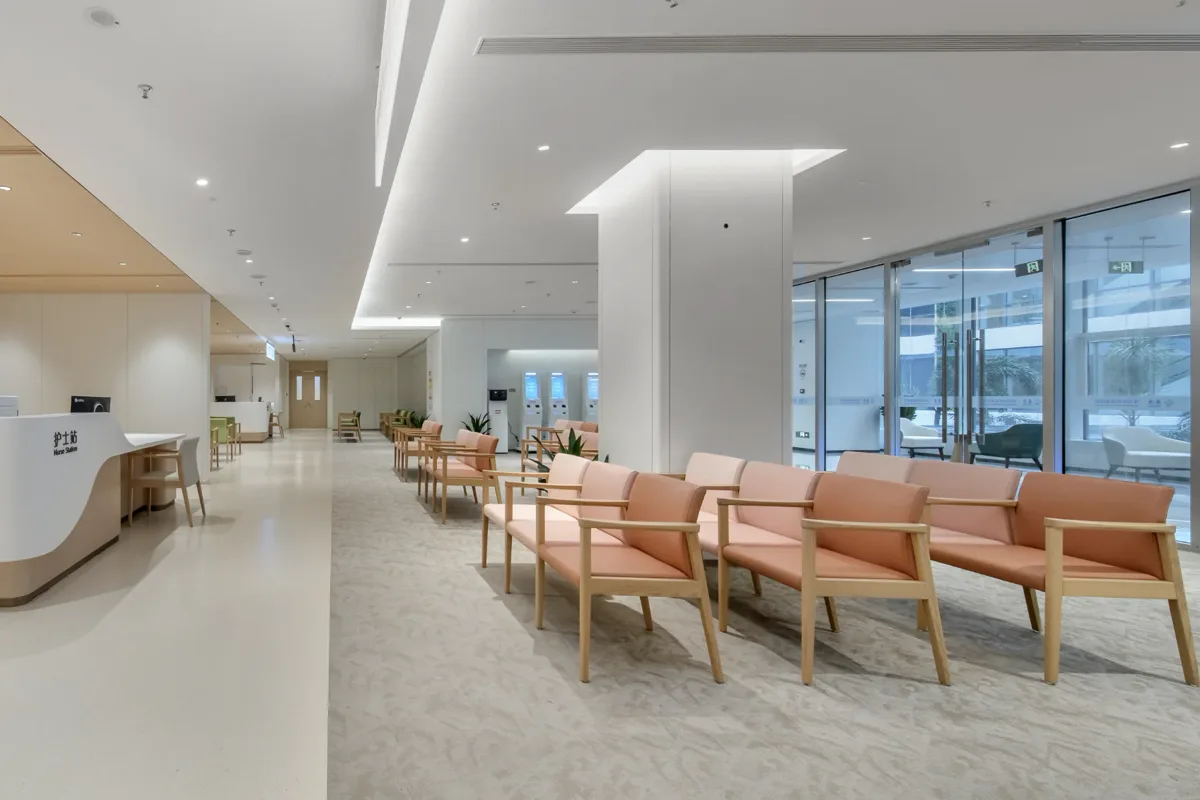 Peach waiting chairs beside a counter signed Ultrasound and Nurse Station in English and Chinese, at the Shenzhen partner facility