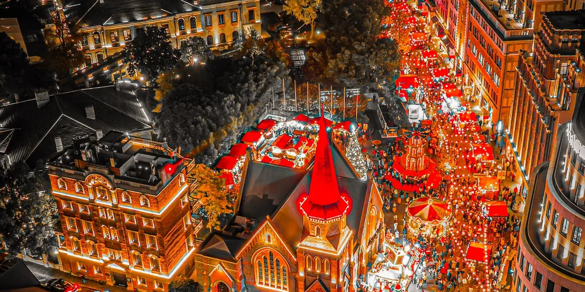 Aerial night view of Waitanyuan (外滩源) Christmas market around the former Union Church—red-roof wooden stalls, string lights, and crowds in Shanghai’s Bund historic district