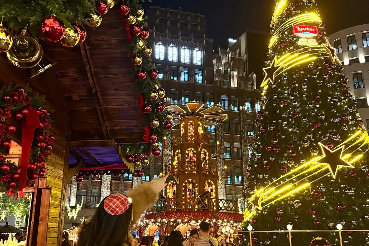 German-style Christmas pyramid and tall lit tree with Loacker branding at a Shanghai outdoor Christmas market plaza at night