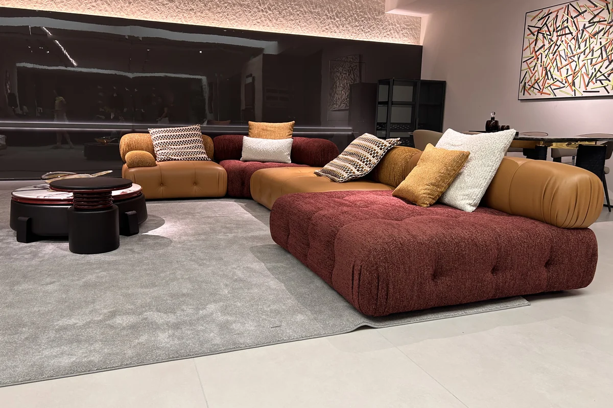 Modular sofa in burgundy fabric and caramel leather with a low round coffee table in a Lecong furniture showroom, Shunde, Foshan