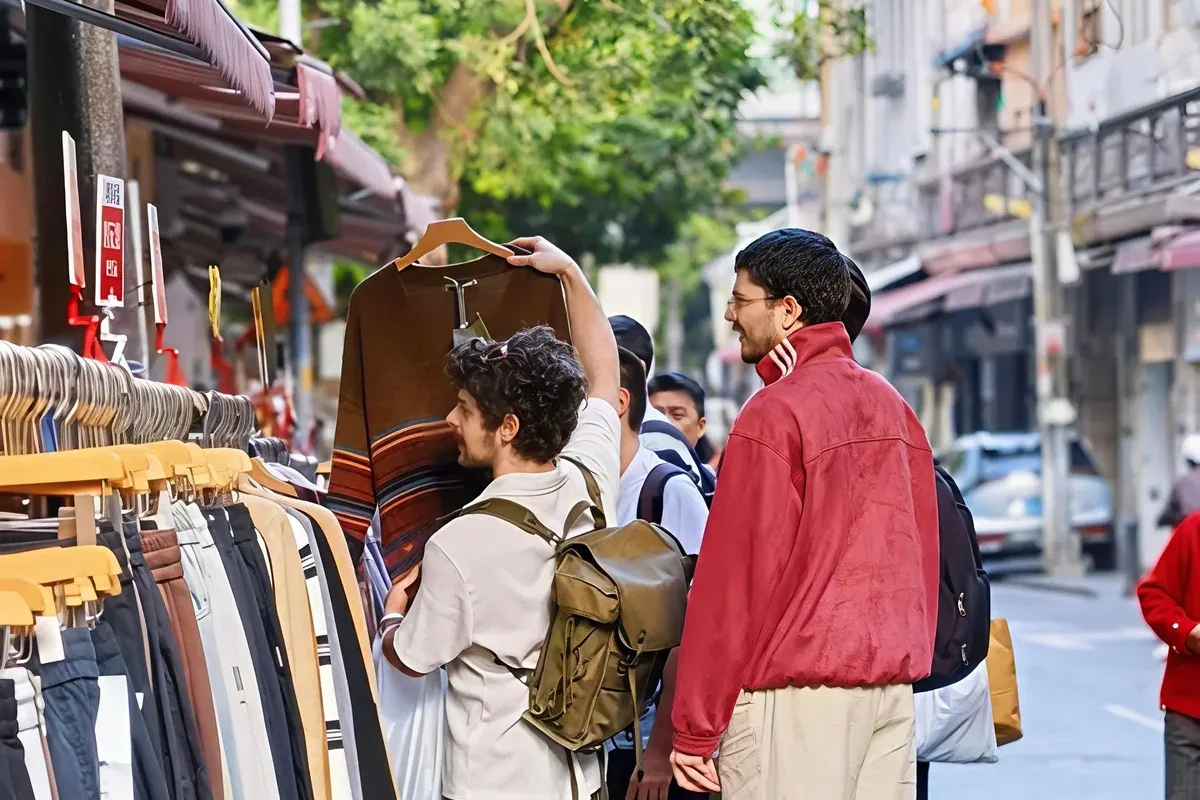 Travellers browsing clothing racks on a Guangzhou wholesale clothing street
