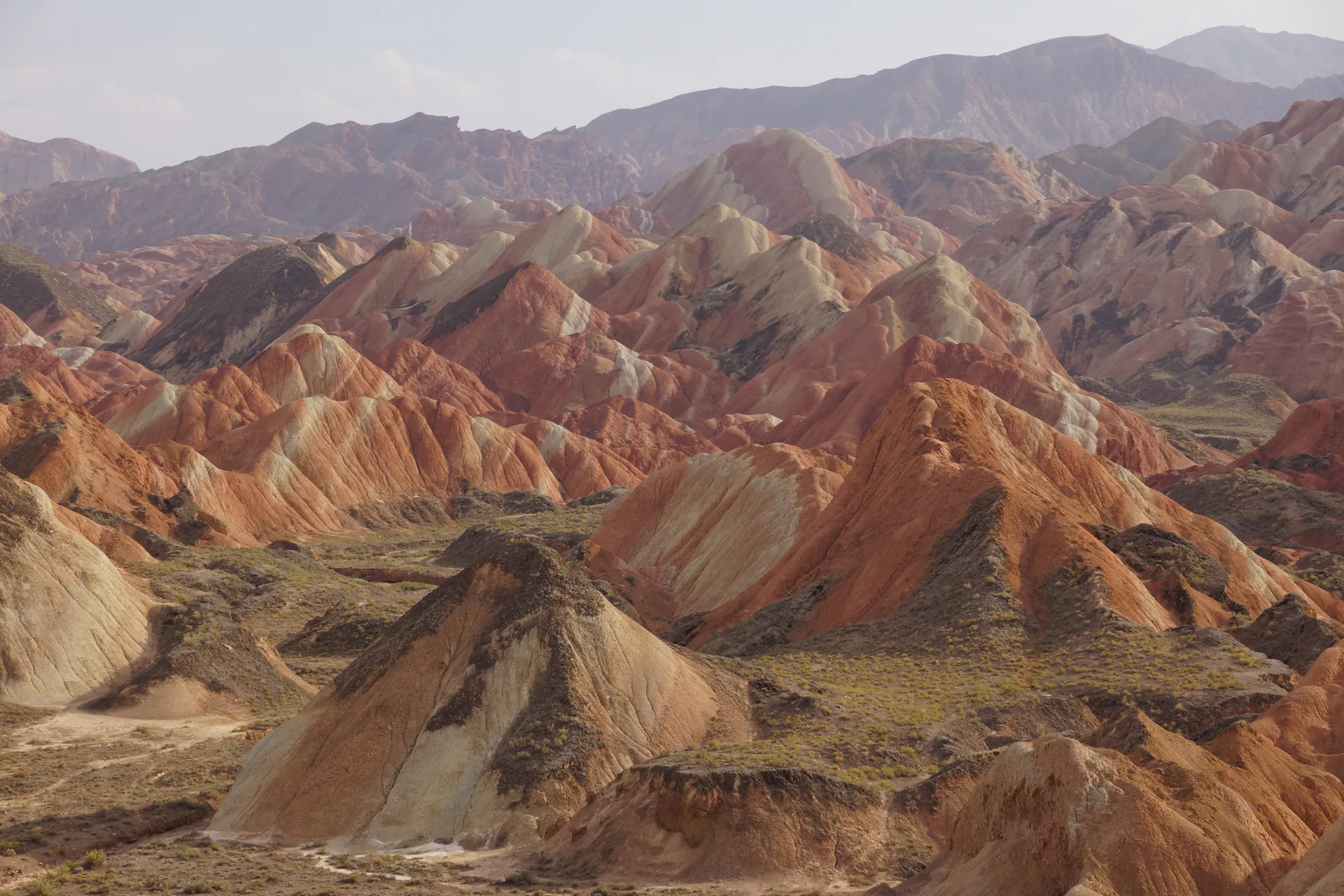 Visitors on a wooden boardwalk above the red and yellow striped hills of Zhangye Danxia in Gansu