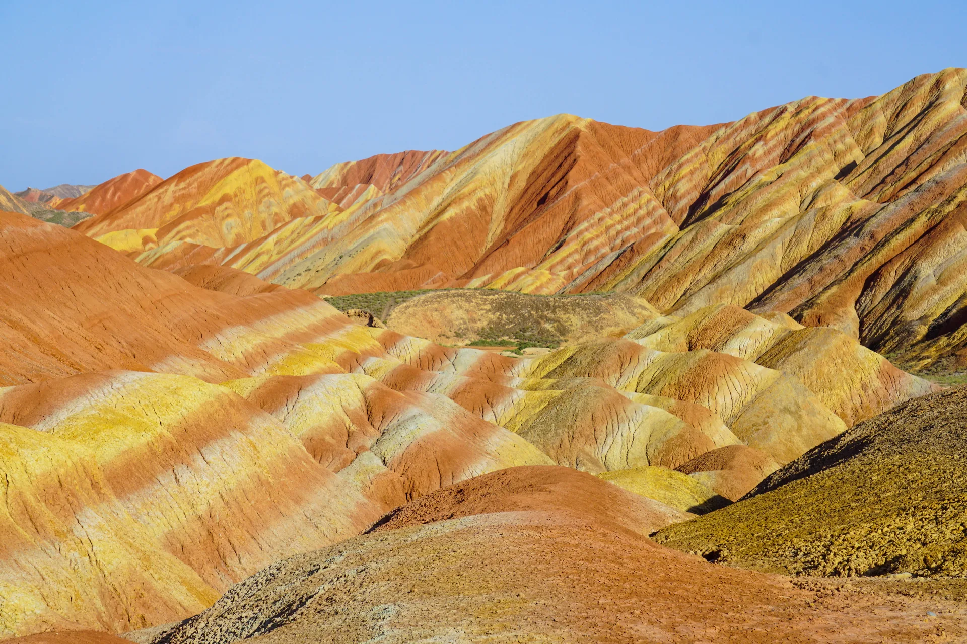 Striped red, ochre, and cream hills of Zhangye Danxia, the Rainbow Mountains, with a viewing platform in the foreground at Zhangye National Geopark
