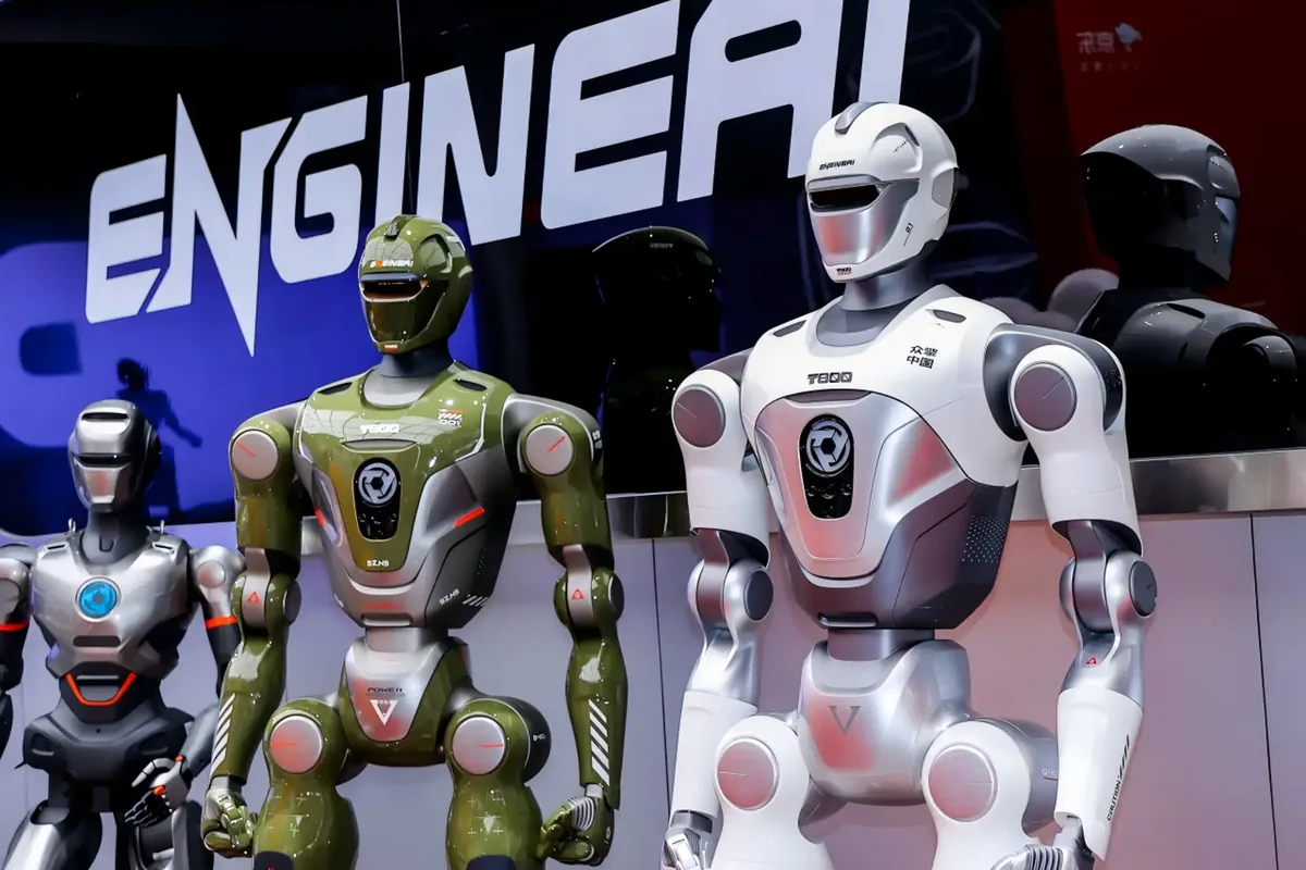Three EngineAI humanoid robots in green, silver and white standing in front of an illuminated EngineAI logo at a trade display